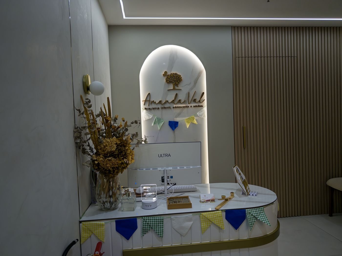 Recepção da Dra. Amanda Val com a marca iluminada e flores secas